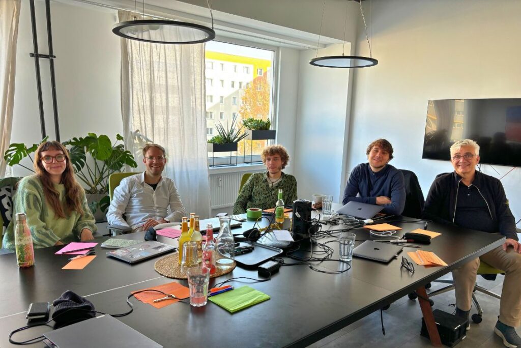 Gruppenfoto am Workshoptisch voller Bunter Zettel und digitaler Geräte