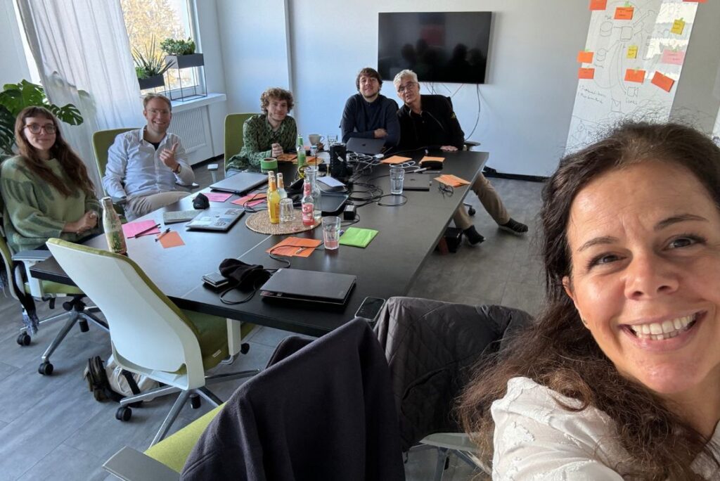 Melina macht ein Selfie mit den anderen Workshopteilnehmern am Tisch hinter ihr